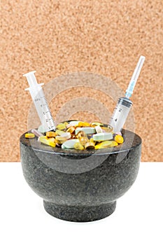 Bowl of pills and syringes addiction concept