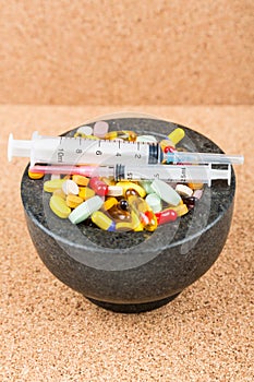 Bowl of pills and syringes addiction concept