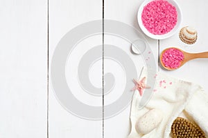 Bowl with pink bath salt, wooden spoon, towel, soap starfish, spa brush on wooden surface. Spa procedure concept with bath salt,