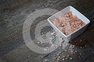 Bowl of Pink Himalayan Salt on a rustic wood plank board with room for copy space
