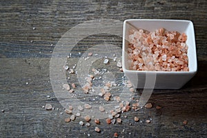 Bowl of Pink Himalayan Salt on a rustic wood plank board with room for copy space