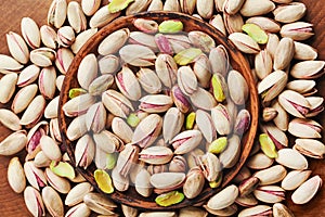 Bowl of pistachio nuts on wooden table top view. Healthy food and snack.