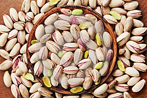Bowl of pistachio nuts on wooden table top view. Healthy food and snack. photo