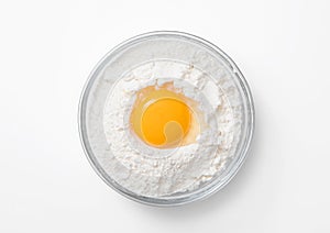 Bowl plate with flour and egg yolk on white background