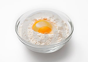 Bowl plate with flour and egg yolk on white background