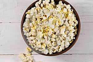 Bowl with popcorn on wooden table