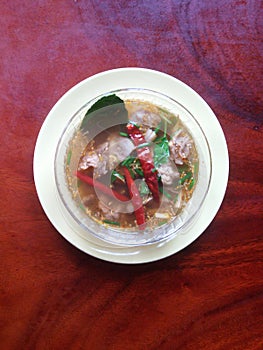 A bowl of pork ribs with red ant ovum spicy soup.