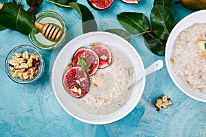 A bowl of porridge with figs slices and walnuts on blue background.