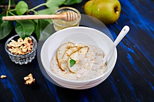 A bowl of porridge with pears slices and walnuts.