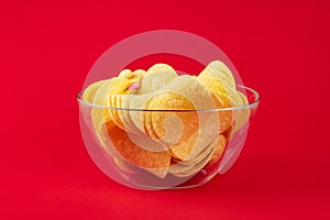 Bowl of potato chips in bright red background. Minimalistic image of attention grabbing fast food in vivid colors