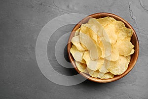 Bowl of potato chips on grey table, top view