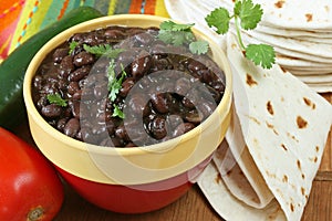 Bowl of prepared black beans with tortillas photo