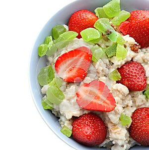 Bowl with prepared oatmeal, candied fruit and strawberry on white background