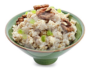 Bowl with prepared oatmeal, candied fruit and walnuts on white background