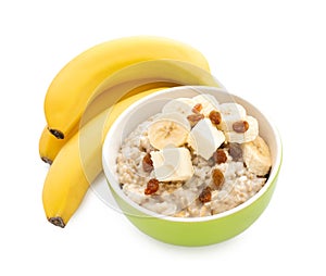 Bowl with prepared oatmeal, raisins and bananas on white background