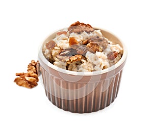 Bowl with prepared oatmeal and walnuts on white background