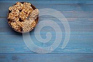 Bowl of puffed rice bars kozinaki on light blue wooden table, above view. Space for text
