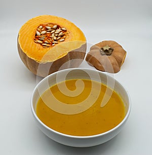 A bowl with pumpkin cream soup vellutata di zucca isolated on white background