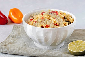 Bowl of quinoa cooked with red and yellow bell pepper and spinach