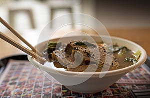 A bowl of ramen from a restaurant on a tray. Japanese ramen soup with pork, egg and chives