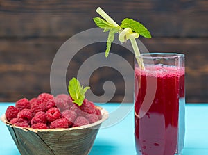 Bowl of raspberries and glass of juice with straw