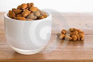 Bowl of raw almond nuts on wooden table