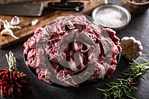 Bowl of raw cuts of beef with herbs and garlic ready for making a hearty soup or stew