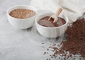 Bowl of raw natural organic linseed flax-seed with spoon and powder on light table background with linen cloth