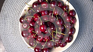Bowl of red cherries on table. Rotating sweet cherry plate.