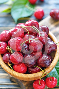 Bowl with red cherries in water drops closeup.