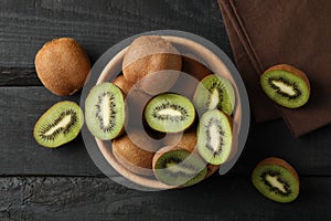 Bowl with ripe kiwi on wooden background