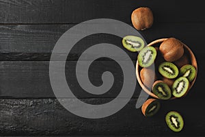 Bowl with ripe kiwi on wooden background