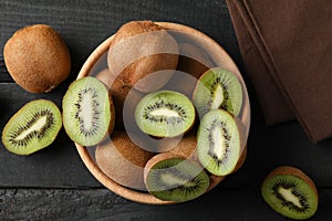 Bowl with ripe kiwi on wooden background