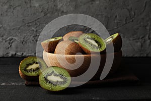 Bowl with ripe kiwi on wooden table