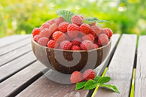 Bowl with ripe raspberries on the table in the garden