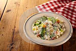Bowl of risotto risi bisi and veggies beside checkered napkin photo