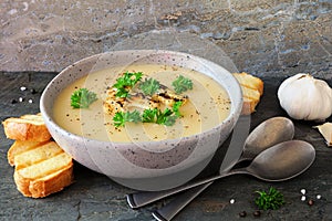 Bowl of roasted cauliflower and potato and soup, side view table scene with a dark stone background