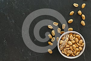 Bowl with roasted and salted peanuts on a slate with copy space