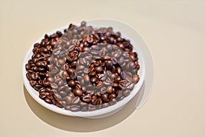 A bowl of robusta coffee beans, on beige