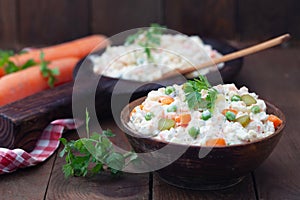 Bowl of russian salad olivier with meat and vegetables on a wooden table