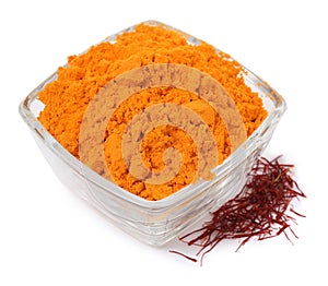 Bowl with saffron powder and dried flower stigmas on white background