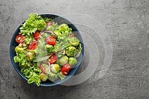 Bowl of salad with Brussels sprouts on grey background, top view.