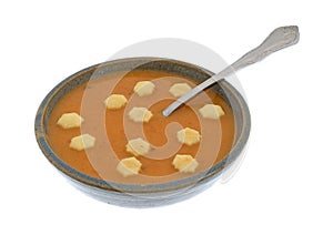 Bowl of salmon bisque soup with a spoon and crackers