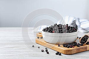 Bowl and scoop with dried blueberries on white wooden table. Space for text