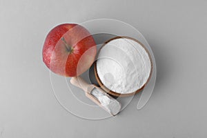 Bowl, scoop with sweet fructose powder and ripe apple on white background, top view
