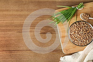 Bowl with seeds and wheat grass on wooden background, flat lay