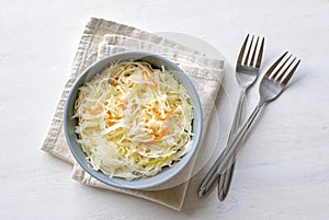 Bowl of shredded saurkraut on towel and two forks