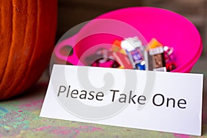 Bowl sitting on a doorway with a sign stating to please take one for Halloween trick or treaters.