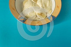 Bowl of sliced banana and yoghurt in a bowl on bright blue background - minimal, copy space