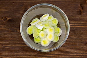 Bowl with sliced leek on wooden top